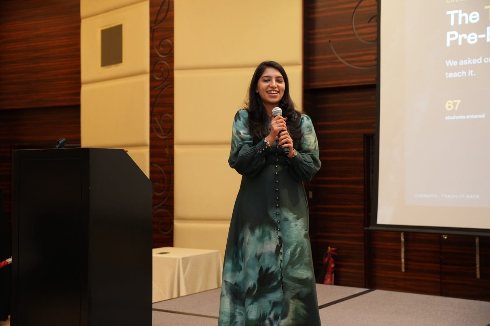 Divykriti Madaan presenting the Teach-It-Back contest results on stage in Dubai