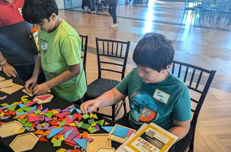 Children solving hands-on math puzzles at a Cuemath math event.