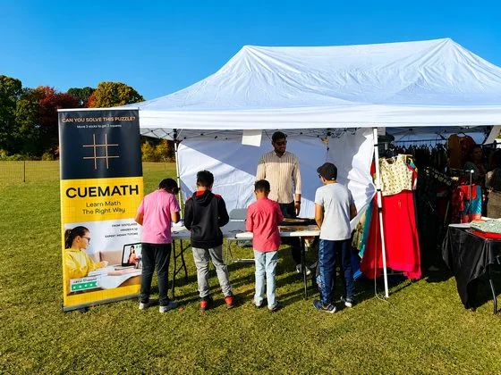Children solving a puzzle at an outdoor Cuemath booth.